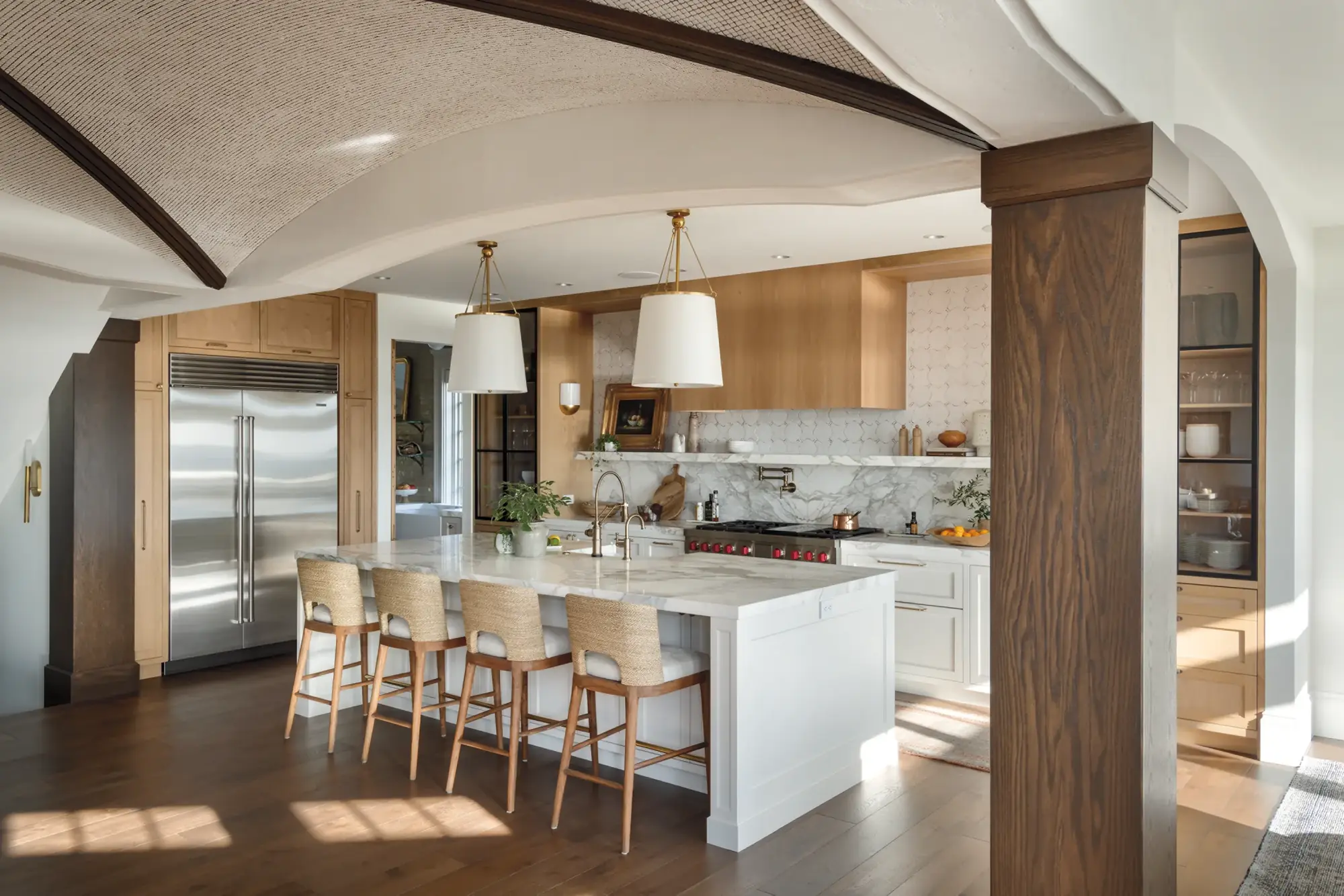 A calm kitchen with a Sub-Zero side-by-side built into pale oak cabinetry under an arched ceiling